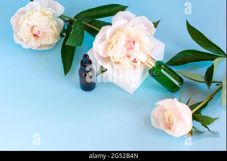 Luxurious cosmetic bottles with antiaging skincare product on background with peony flowers, blank label packaging for body care branding design. Stock Photo