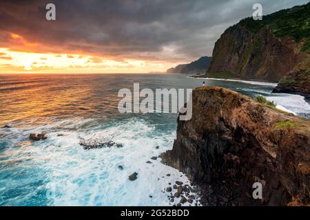 One man admiring sunrise over the ocean from top of cliff, Madeira island, Portugal Stock Photo