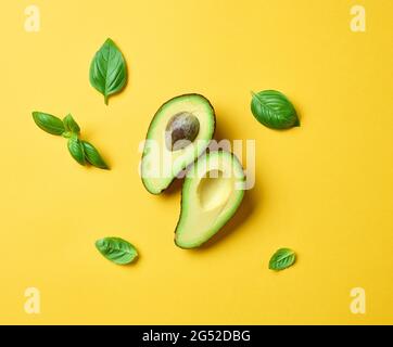 fresh avocado and basil leaves on yellow background, top view Stock Photo