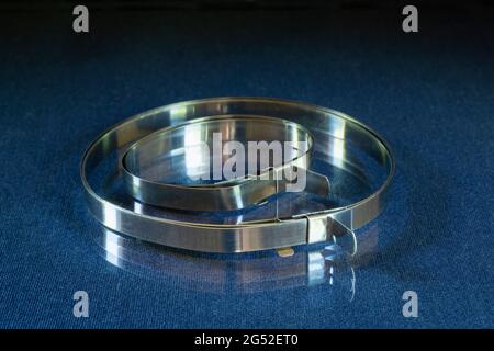 A steel band clamp rests on a table with a reflection. Repair tools on a black background Stock Photo