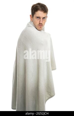 Young handsome tall slim white man with brown hair looks grumpy with blanket isolated on white background Stock Photo
