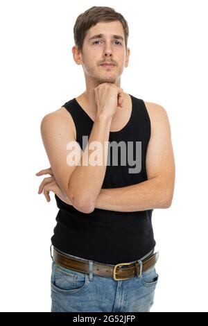 Young handsome tall slim white man with brown hair with one hand supporting his head in black undershirt isolated on white background Stock Photo