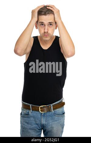 Young handsome tall slim white man with brown hair is desperate in black undershirt isolated on white background Stock Photo
