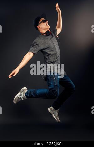 Full length image of man which listening to music and jumping in studio. Vertical image Stock Photo