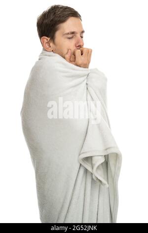 Young handsome tall slim white man with brown hair with his eyes closed with blanket isolated on white background Stock Photo