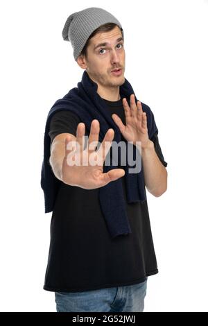 Young handsome tall slim white man with brown hair holds you back in black shirt with gray winter hat isolated on white background Stock Photo