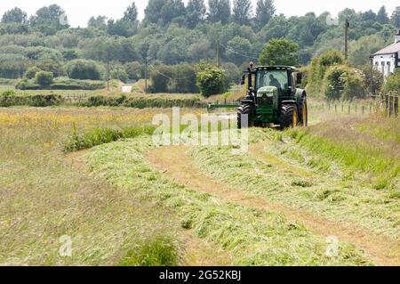 A farmer taking advantage of a warm dry spell to cut his grass. Stock Photo