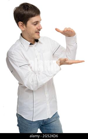 Young handsome tall slim white man with brown hair holding invisible object in white shirt isolated on white background Stock Photo