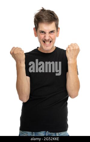 Young handsome tall slim white man with brown hair looking crazy with clenched fists in black shirt isolated on white background Stock Photo