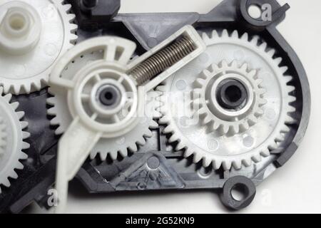 multiple reducer gears of white plastic, spring and black case are parts of inkjet printer paper feeder mechanical drive Stock Photo