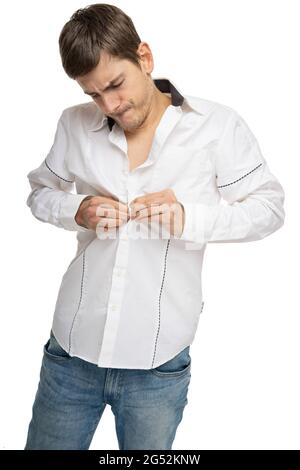 Young handsome tall slim white man with brown hair buttoning his white shirt isolated on white background Stock Photo