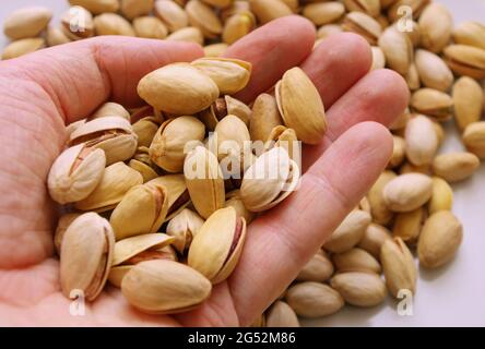 Hand holding pistachio nuts. Healthy food and snacks. Nuts, pistachios. Background of nuts. Top view or flat lay. Tasty pistachios as background. Stock Photo