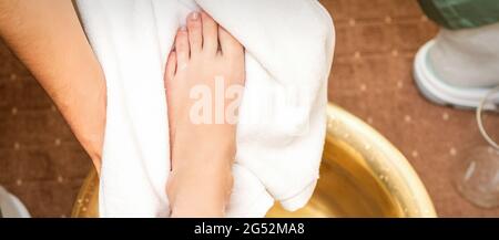 Top view close up of male therapist drying leg of a white woman with a towel after washing in a spa beauty salon Stock Photo