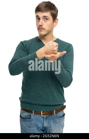 Young handsome tall slim white man with brown hair shows fist on his palm in dark green sweater isolated on white background Stock Photo