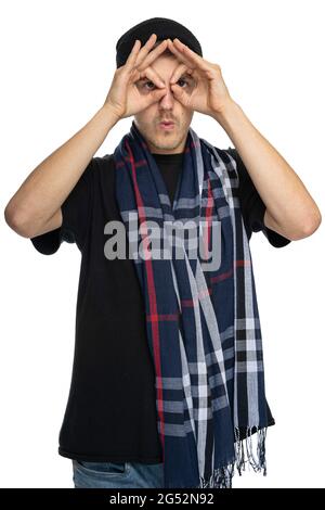 Young handsome tall slim white man with brown hair doing binoculars with his hands in black shirt with scarf isolated on white background Stock Photo