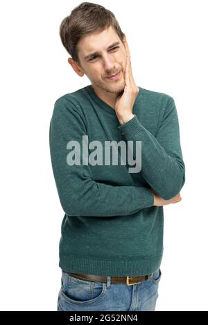 Young handsome tall slim white man with brown hair with toothache in dark green sweater in blue jeans isolated on white background Stock Photo
