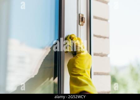 Woman in gloves washes the window frame with a cleaning rag. Stock Photo