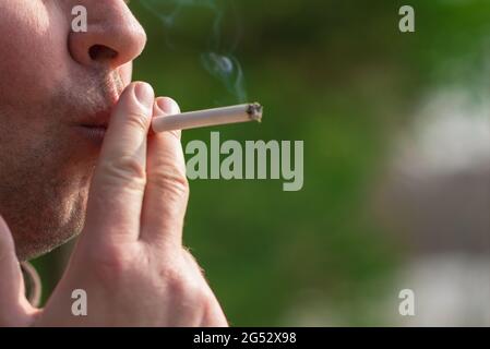 Cropped close up man smoking cigarette outdoors shot. Stock Photo