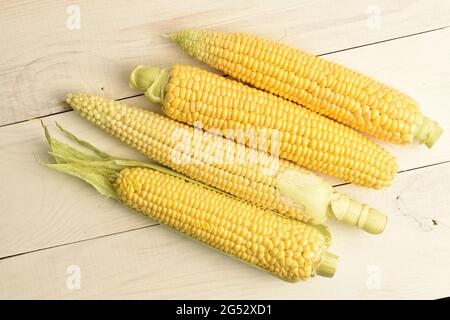 Four cobs of sweet organic corn, close-up, on a white wooden table, top view. Stock Photo