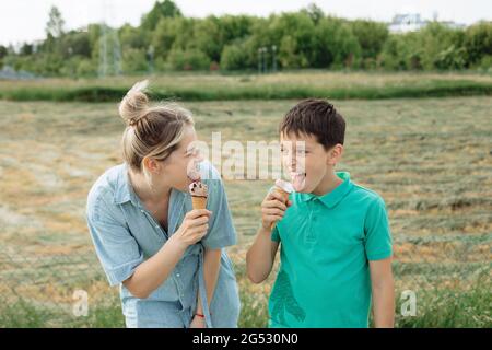 young woman laughs with her son together. Eat ice cream on summer day, green. Happy moments Stock Photo