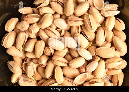 Organic salted delicious pistachios in a black plate, close-up,  top view. Stock Photo