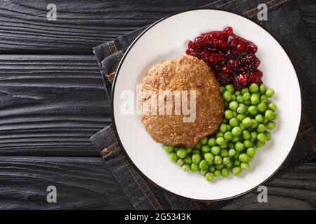 Rich and delicious Swedish veal patties Wallenbergare with boiled green peas closeup in the plate on the table. Horizontal top view from above Stock Photo