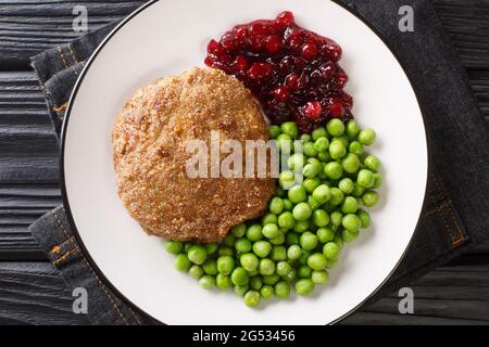 Wallenbergare is a Swedish dish generally consisting of ground veal is traditionally served with boiled green peas closeup in the plate on the table. Stock Photo