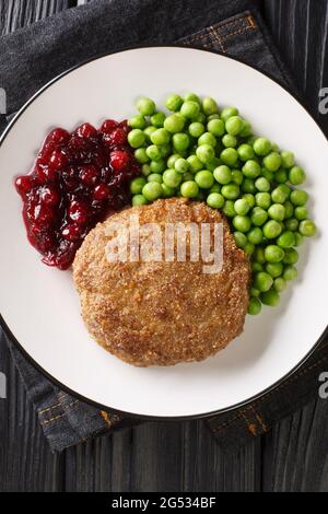 Swedish food Veal burgers Wallenbergare with green peas closeup in the plate on the table. Vertical top view from above Stock Photo