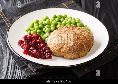 Delicious veal meatball with green peas garnish and lingonberry jam close-up in a plate on the table. horizontal Stock Photo