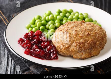 Rich and delicious Swedish veal patties Wallenbergare with boiled green peas closeup in the plate on the table. Horizontal Stock Photo