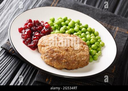 Swedish Luxurious Wallenbergare veal patties with green peas closeup in the plate on the table. Horizontal Stock Photo