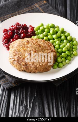 Swedish food Veal burgers Wallenbergare with green peas closeup in the plate on the table. Vertical Stock Photo
