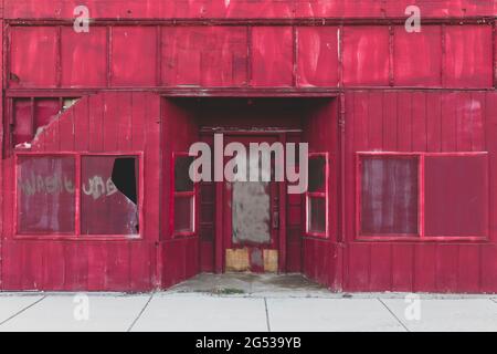 Boarded up building with broken windows on a main street Stock Photo