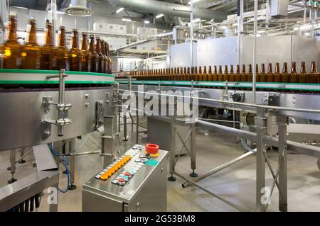 Beer bottling plant with moving belts, rows of bottles, automated process, capping and labelling and placing in crates Stock Photo
