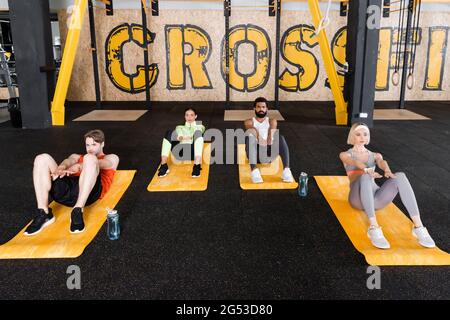 young multiethnic people doing abs exercise on fitness mats Stock Photo