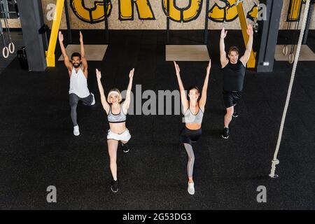 high angle view of multiethnic people doing forward lunge exercise with raised hands Stock Photo