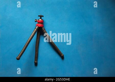 View from top of a camera accessory tripod on a blue background Stock Photo