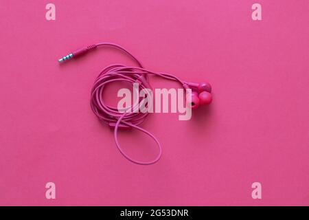 pink headphones with rolled wire, on a pink background Stock Photo