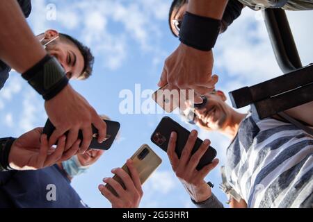A group of young sporty men get together and use the smartphone, photo from below, concept of group, community and unity. Stock Photo