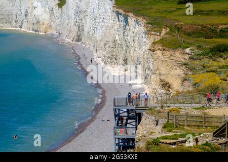 Staycation idea. People walk on the stairs to access Beachy Head Beach next to the English Channel at Birling Gap, East Sussex, England. Stock Photo