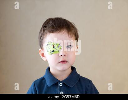 Little boy with okluder on the eye. Stock Photo