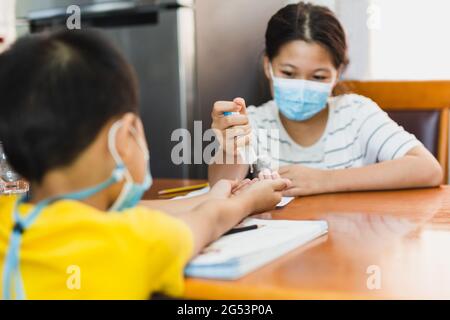 Elder sister applying hand sanitizer to her small brother to clean his hand. Stock Photo