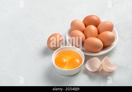 Chicken eggs and raw yolks on a gray background. Side view, copy space. Stock Photo