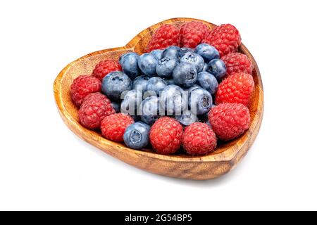 Raspberry and blueberry in wooden bowl in the shape of heart isolated on white background. Stock Photo