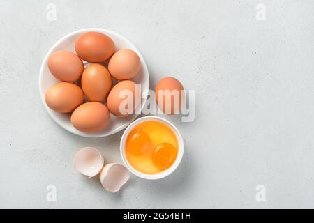 Raw chicken eggs and egg yolks on a gray concrete background. Top view, copy space. Stock Photo