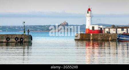 Newlyn Harbour and the picturesque lighthouse on the south pier wall, with St Michael's Mount in the distance. Stock Photo