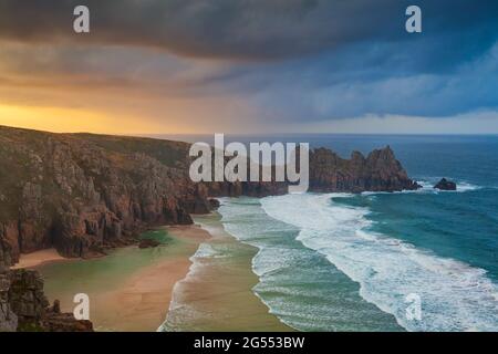 View from Treen Cliff over Pendvounder Beach near Porthcurno in Cornwall on a stormy summer morning, with the headland of Treryn Dinas in the distance Stock Photo