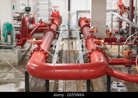 Red pumps of water supply system in basement of building. Stock Photo