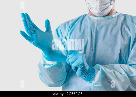 A medic in a protective suit puts on medical gloves. Personal protection for the coronavirus pandemic infection virus covid 19. Protective medical equ Stock Photo