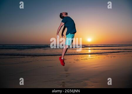 Man jumping on beach, silhouette in the sunset. Feel good and freedom concept. Stock Photo